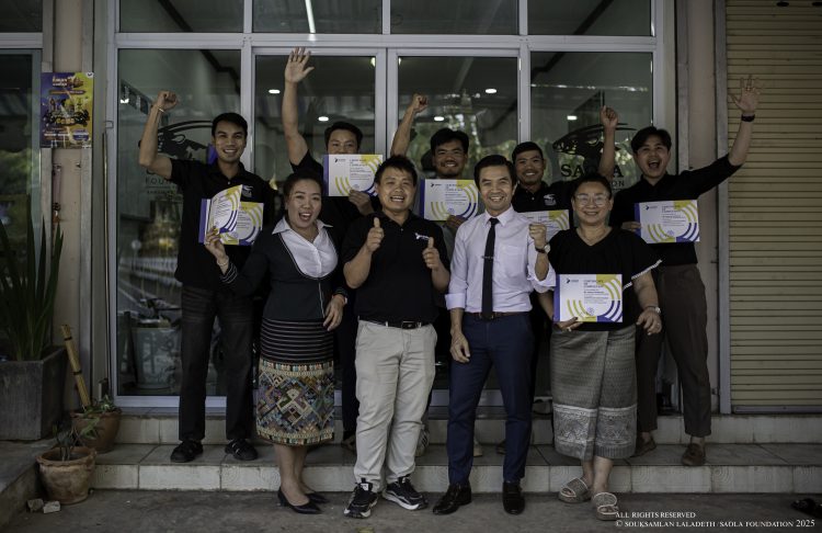 Saola Foundation team members holding certificates and celebrating outside a building